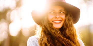 Woman who is happier than average smiles in the setting sun despite times being hard