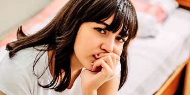 A portrait of a woman with bangs and an intense, observant expression; illustrating the 'female autism phenotype' and how social expectations often hide neurodivergent traits behind a facade of quirkiness or shyness.