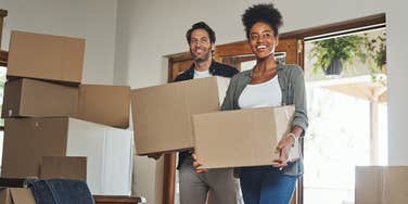 couple carrying moving boxes into new home