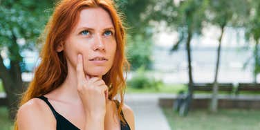 high-iq woman deep in thought standing outside