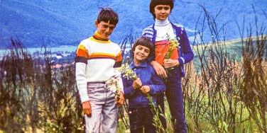 three boys from the 1960s and 1970s standing in the grass smiling