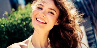 A woman showcasing happiness and style in a charming outdoor setting; illustrating the 'low-reactivity' and warmth that psychologists identify as key drivers of instant social attraction.