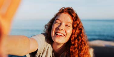 A carefree woman smiling happily at the camera during summer; illustrating the 'emotional clarity' that arrives after a person successfully navigates the challenging feelings that precede a lasting life change.