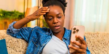 anxious woman looking at her phone canceling plans via text