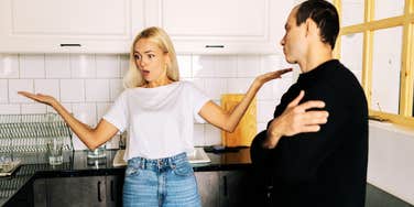 A blonde woman blaming her husband while he looks away in frustration; illustrating the 'blame-shifting' and repetitive linguistic patterns that experts identify as red flags for a lack of personal integrity.