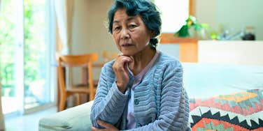 retired older woman sitting at home alone feeling guilty