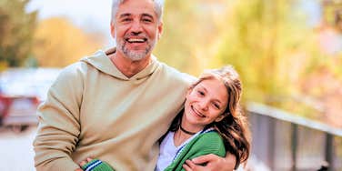 genuinely good parent hugging his daughter outside