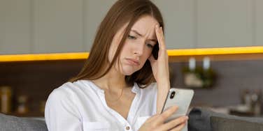 millennial woman annoyed with social media looking at smartphone