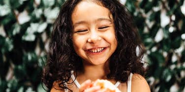 A portrait of a joyful girl enjoying her free time; illustrating the 'slow parenting' philosophy of protecting a child's mental health by refusing to enforce hours of after-school assignments.