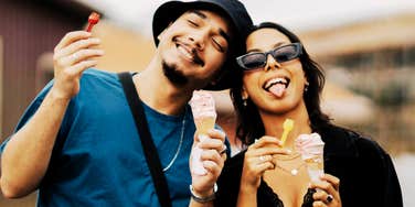 A portrait of a young couple sharing a lighthearted moment with ice cream; illustrating the research-backed concept of being 'on the same wavelength' through mirrored body language and shared emotional resonance.