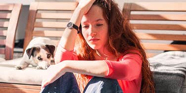 Young adult woman with her dog looking sad due to scarring childhood experiences