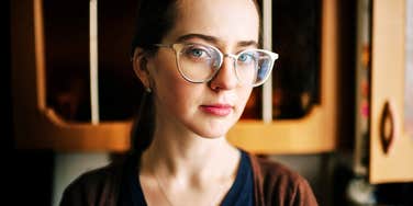 Lonely young woman with glasses alone in a kitchen 