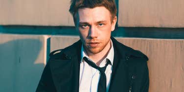 messy serious man acting like a total loser standing outside 