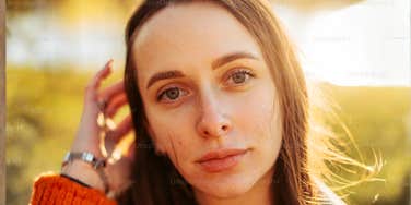 A portrait of a woman looking serene and observant in an outdoor setting; illustrating the specific habits and mindful awareness that allow naturally intuitive people to navigate life's uncertainties.