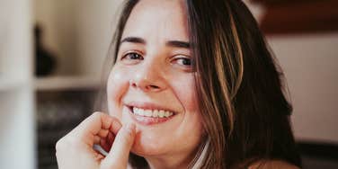 A portrait of a woman with a genuine, welcoming smile; illustrating the positive body language and 'soft skills' that high-EQ individuals practice to keep conversations flowing smoothly.