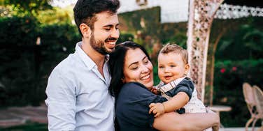 A portrait of parents embracing and admiring their young child, capturing the 'foundational bond' and the quiet, intentional choices that define successful parenting in the modern age.