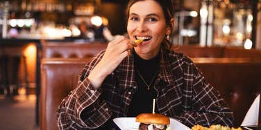 young woman eating at a restaurant that's secretly making her overeat