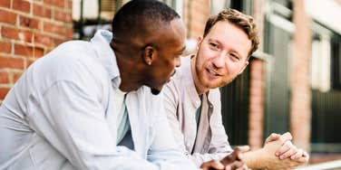 Two men talking in a professional setting with open and honest body language; illustrating the 'steady presence' and ethical interpersonal habits that experts identify as the most respected markers of a trustworthy individual.