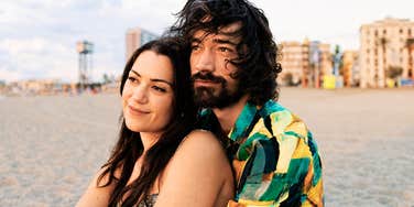 A man and woman in a deep embrace watching the sunrise over the ocean; illustrating the 'enmeshed attachment' and the physiological addiction to emotional highs and lows that characterize a trauma bond.