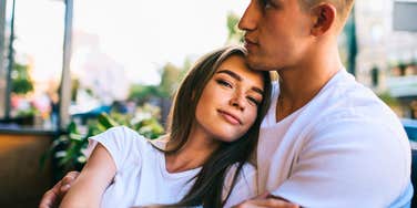 happy woman leaning into arms of her supportive partner