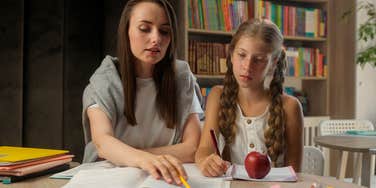 teacher helping student with work sitting at desk