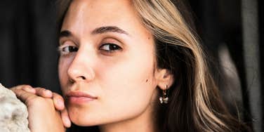 A woman looking straight into the lens with a piercing and observant expression; illustrating the 'constant monitoring' and psychological dominance cues that experts identify as early indicators of a controlling personality.