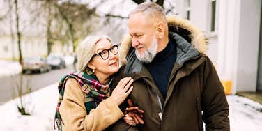 A senior man and woman walking side-by-side on a city sidewalk; illustrating the 'emotional co-regulation' and consistent non-verbal cues that characterize individuals with superior social and self-awareness.