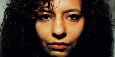 A close-up portrait of a young woman with a deep, contemplative expression; a visual representation of 'self-silencing' and the quiet emotional retreat that occurs when a person begins to lose their identity in a relationship.