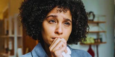worried woman looking at a phone with an alarmed expression; illustrating the 'digital secrecy' and unexplained changes in routine that psychologists identify as the most common indicators of infidelity.