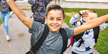 A group of energetic schoolchildren having fun on a school background; illustrating the dramatic improvement in student engagement and morale following an experimental shift in the Texas school day.
