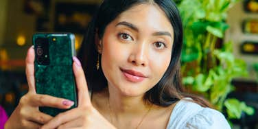 intelligent woman smiling while holding her phone but not using the internet