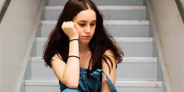 A young student looking dejected while sitting in a school hallway; illustrating the lasting emotional trauma that can stem from inappropriate or confusing interactions with trusted school authorities.