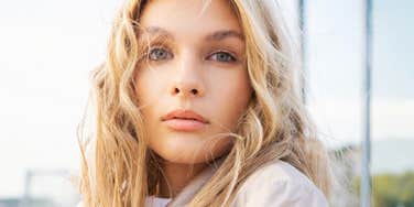 A fashion portrait of a blonde woman looking serene amidst a city backdrop; illustrating the 'grace under pressure' and emotional regulation skills that high-EQ individuals use during personal trials.