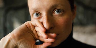 A raw, intimate portrait of a woman looking somber and pensive; illustrating the emotional exhaustion and depression often felt by women in relationships with men who exploit them despite their progressive claims.