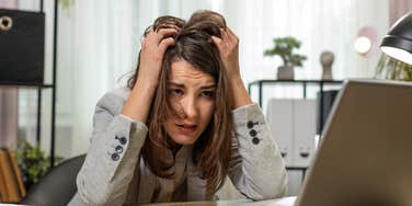 stressed worker sitting at desk in front of laptop