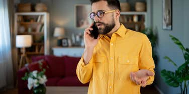 man standing at home talking on phone during tense conversation