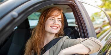 smiling woman sitting in car with window down