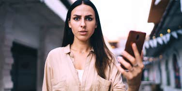 Adult daughter looking shocked at what is being said on her phone