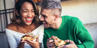 Man and woman laughing and doing better than most people eating pizza