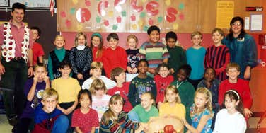 A vintage 1980s classroom photograph from Minneapolis featuring an elementary teacher and students standing in front of a blackboard; a visual representation of 'the archival community' and the nostalgic search for a long-lost educator.