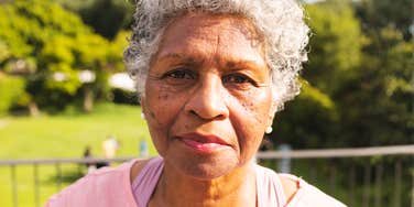 A close-up lifestyle portrait of an elegant mature woman with gray hair looking forward with a calm, knowing expression