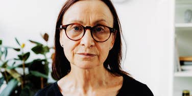 Gen-X female professional focusing intently on the camera through glasses; illustrating Gen-X invisibility' and the frustration of being bypassed for leadership roles despite extensive experience