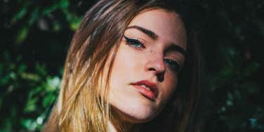 A close-up portrait of a woman looking forward with deep, analytical concentration; illustrating 'micro-expression mapping' and how studying facial tells can forecast a person's next move.