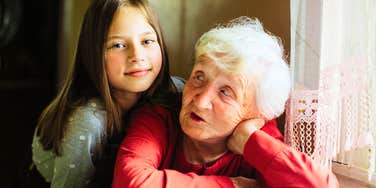 Portrait of a smiling elderly woman with her granddaughter, reflecting the humor and closeness often shared between generations in families