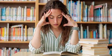 female student struggling to read book