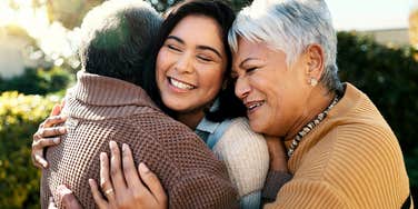 millennial woman hugging her boomer parents with appreciation 