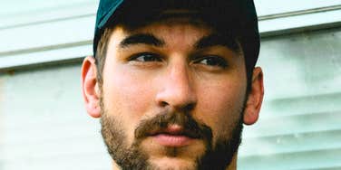 An attractive man wearing a classic baseball hat looking forward with a relaxed, gentle gaze; a visual representation of 'the grounded confidant' and the old-fashioned language that makes a husband irresistible.