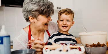 A smiling grandma guiding her young grandchild while mixing ingredients for a cake; illustrating 'respectful boundaries' and the positive behavioral choices made by supportive grandparents to foster a child's independence.
