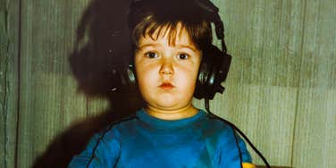 A candid 80s lifestyle snapshot of a little boy with headphones on