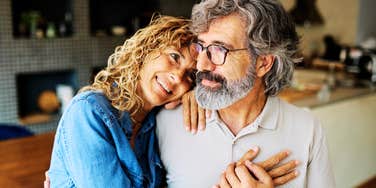 A joyful elderly husband and wife hugging tightly while looking toward the camera; illustrating 'marital longevity' and the old-fashioned conversations that preserve emotional intimacy over decades.